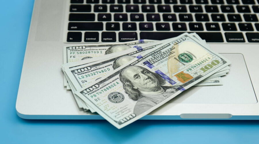 Close up, dollar bills on laptop, money making concept.